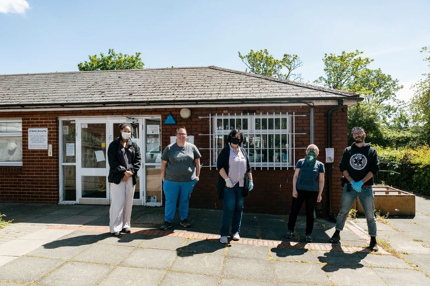 A group of organisers standing outside a community building with masks on.